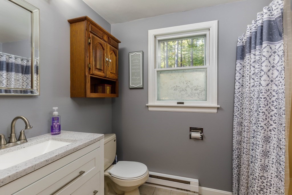 283 Mill Street Gardner, MA 01440 - Photo 10 of 30 a bathroom with a granite countertop toilet a sink a mirror and a window
