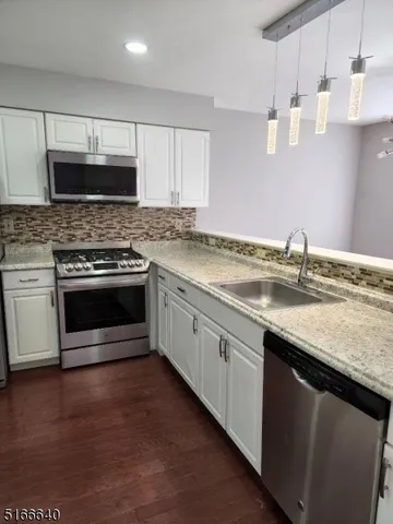 a kitchen with granite countertop a sink cabinets and stainless steel appliances