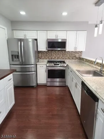 a kitchen with stainless steel appliances granite countertop a refrigerator a stove a sink and a microwave