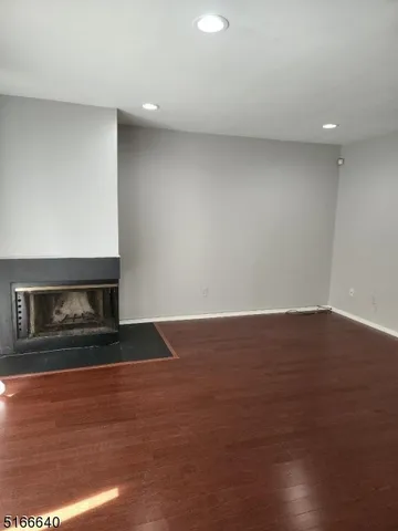a view of empty room with wooden floor and fireplace