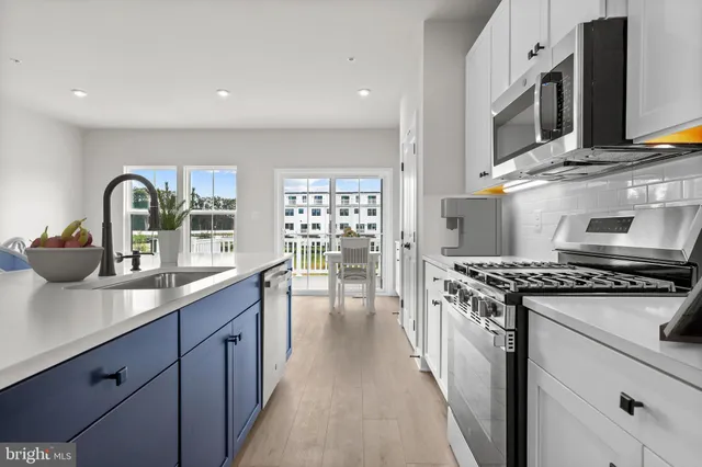 a kitchen with kitchen island granite countertop a refrigerator oven a sink dishwasher and white cabinets with wooden floor