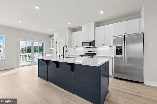 a kitchen with stainless steel appliances granite countertop a table chairs refrigerator and a sink
