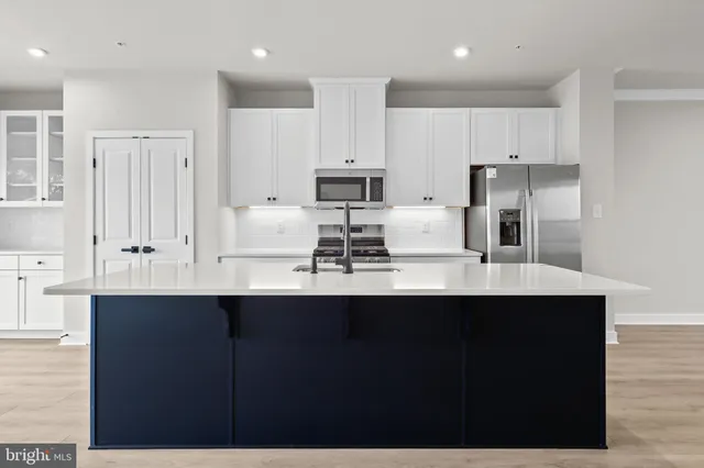 a kitchen with stainless steel appliances granite countertop a table chairs sink refrigerator and microwave