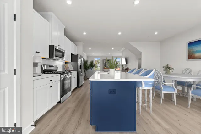 a view of kitchen with kitchen island wooden floor center island and stainless steel appliances