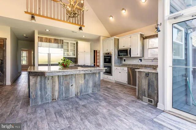 a kitchen with stainless steel appliances kitchen island granite countertop a stove a sink and a refrigerator