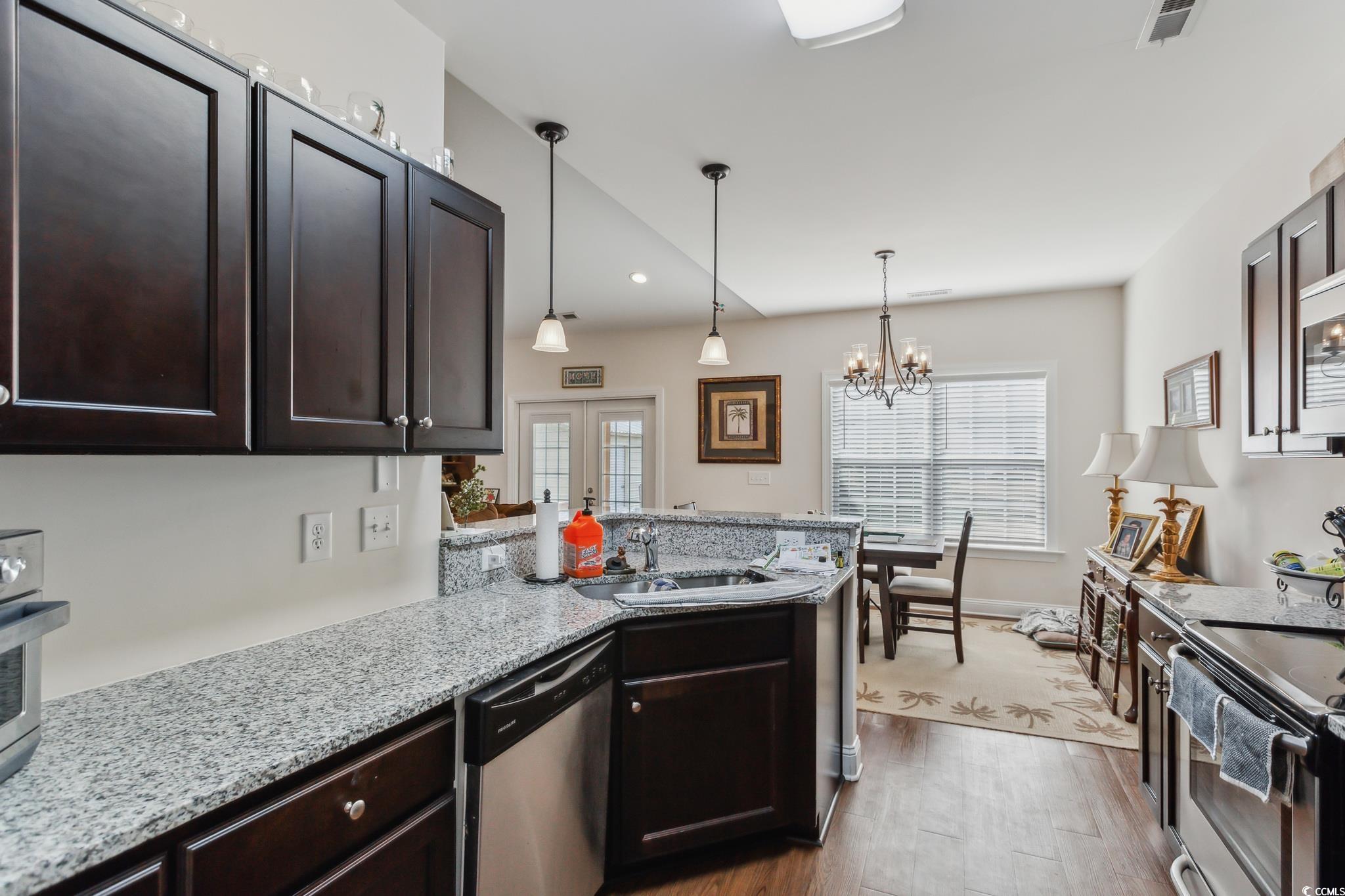 607 Garden Avenue Georgetown, SC 29440 - Photo 4 of 35 Kitchen with sink, light stone counters, decorative light fixtures, dark brown cabinets, and appliances with stainless steel finishes