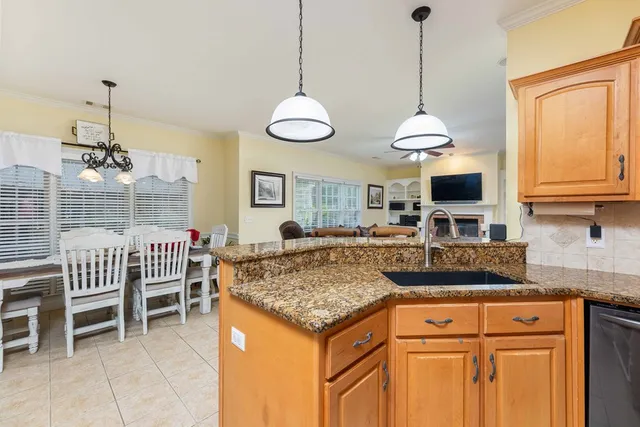 a kitchen with stainless steel appliances granite countertop a stove a sink a dining table and chairs with wooden floor