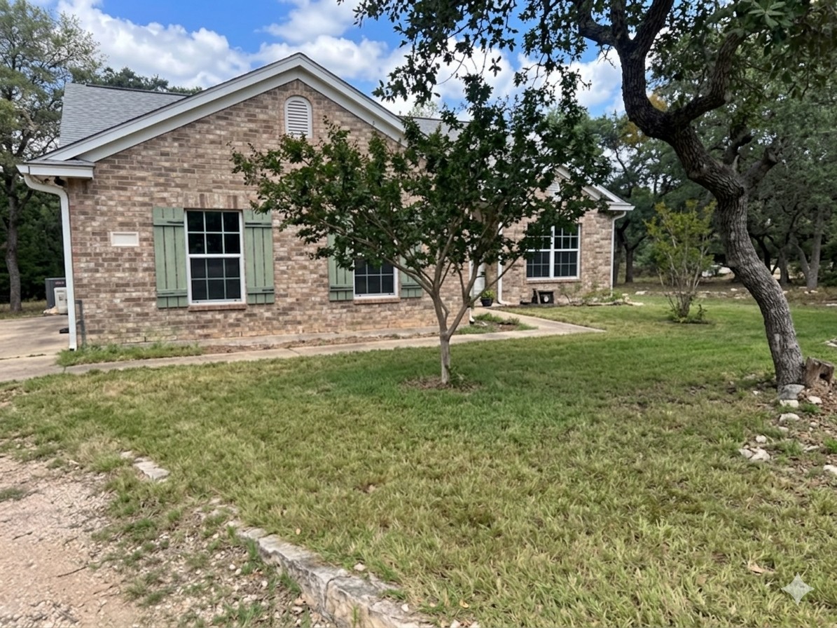 205 Homestead Road Kyle, TX 78640 - Photo 28 of 28 A classic brick facade with charming green shutters graces this welcoming home, nestled amidst mature trees and a verdant lawn.