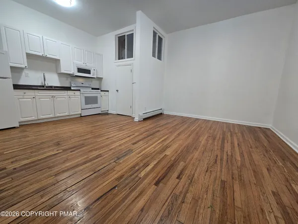 a view of a kitchen with wooden floor and electronic appliances