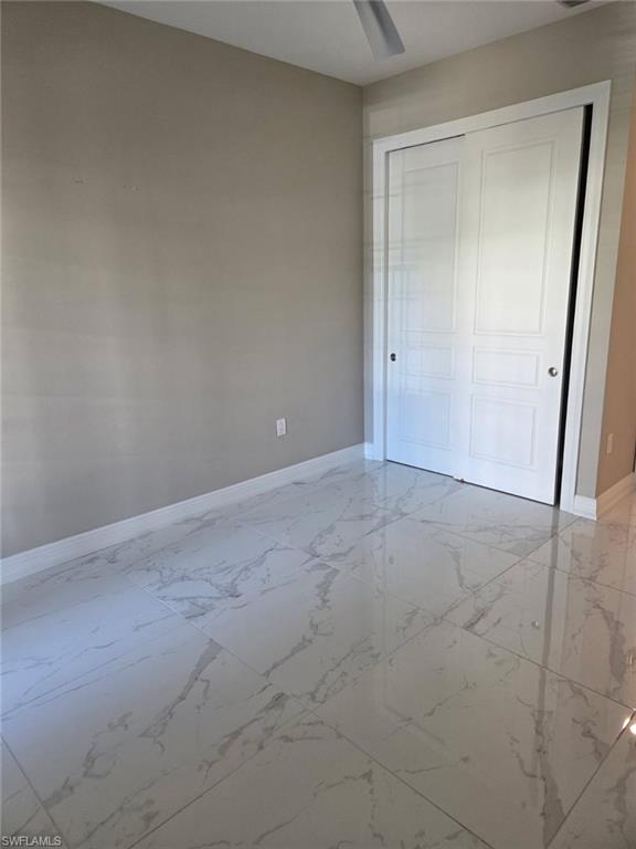 16370 Viansa Way, Unit 6 Naples, FL 34110 - Photo 11 of 27 Unfurnished bedroom featuring light marble finish flooring, a closet, and a ceiling fan