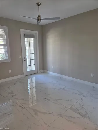 an empty room with windows and chandelier fan