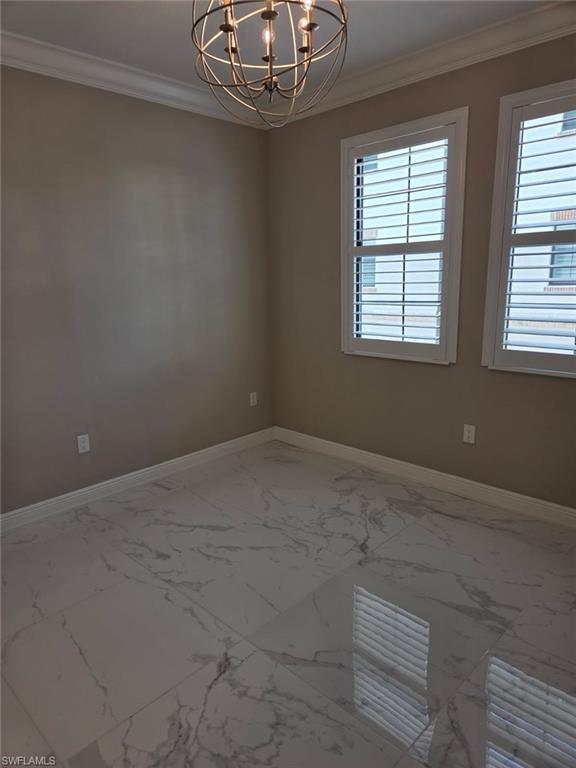 16370 Viansa Way, Unit 6 Naples, FL 34110 - Photo 14 of 27 Empty room featuring crown molding, hanging lights, and light marble finish flooring