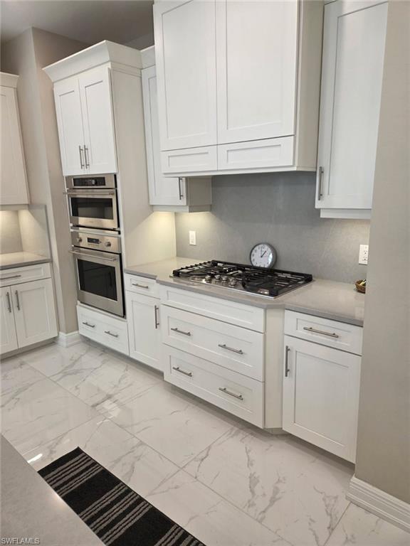 16370 Viansa Way, Unit 6 Naples, FL 34110 - Photo 17 of 27 Kitchen with white cabinets, stainless steel appliances, and light marble finish flooring