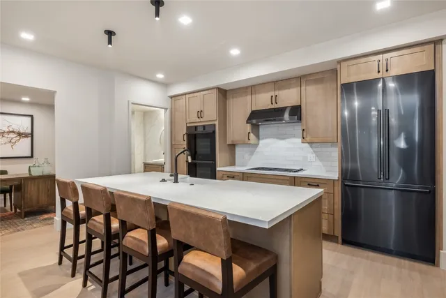 a kitchen with stainless steel appliances refrigerator dining table and chairs
