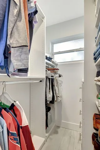 a view of walk in closet with clothes and shoes