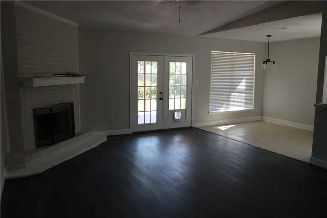 an empty room with floor to ceiling windows and fireplace