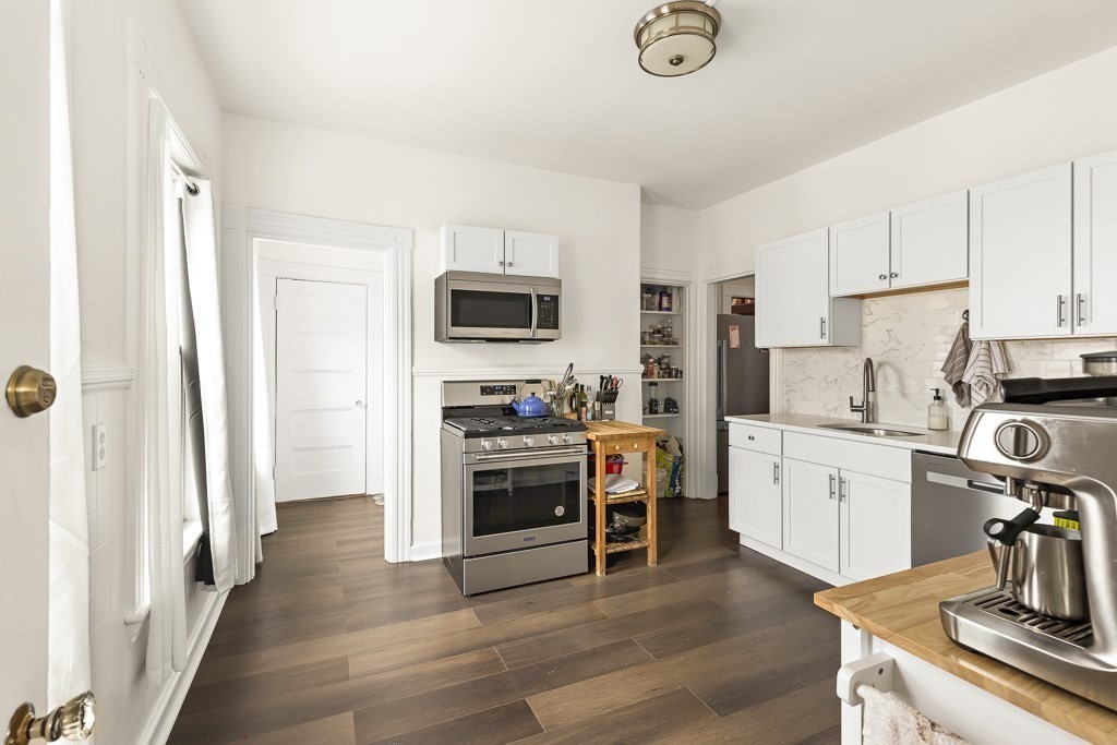 55 Main Street Somerville, MA 02145 - Photo 13 of 28 a kitchen with white cabinets and stainless steel appliances