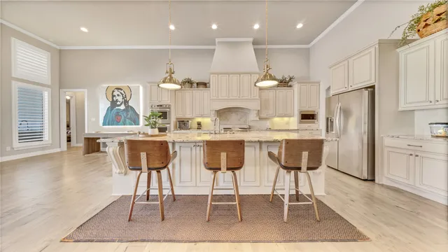 a kitchen with stainless steel appliances kitchen island granite countertop a table chairs sink and cabinets