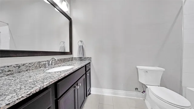 a bathroom with a granite countertop toilet sink and mirror