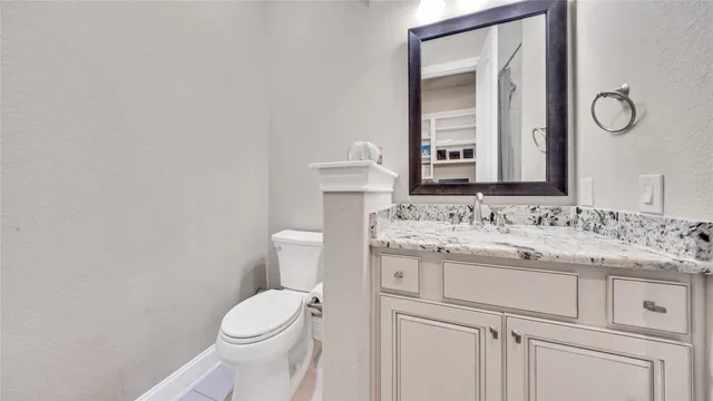 a bathroom with a granite countertop toilet sink and mirror