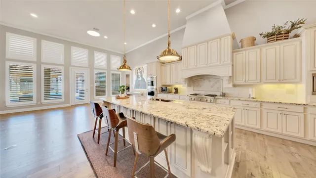 a kitchen with stainless steel appliances granite countertop a stove top oven a sink dishwasher and white cabinets with wooden floor