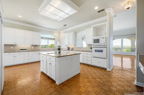 a view of a kitchen with kitchen island a large window cabinets a sink and stainless steel appliances