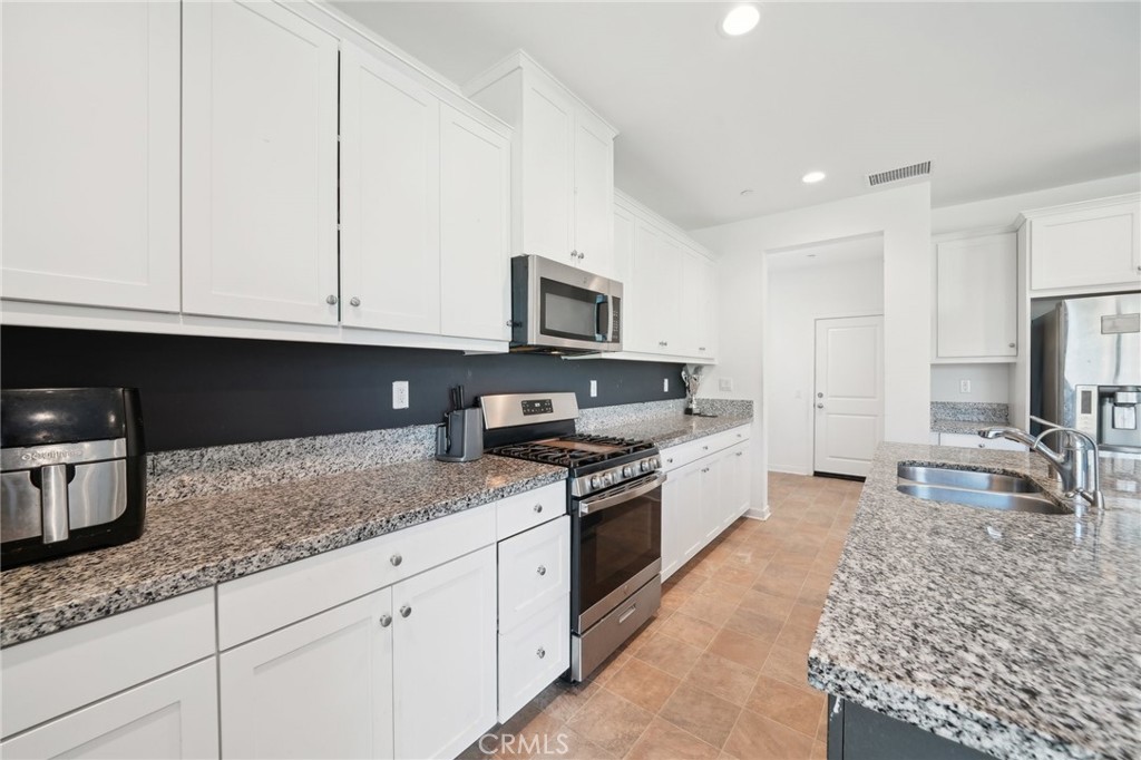 36927 Arezzo Court Beaumont, CA 92223 - Photo 13 of 53 a kitchen with granite countertop a sink dishwasher stove and cabinets with wooden floor