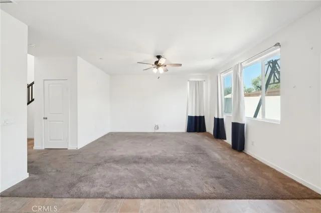 a view of an empty room with kitchen view and a window