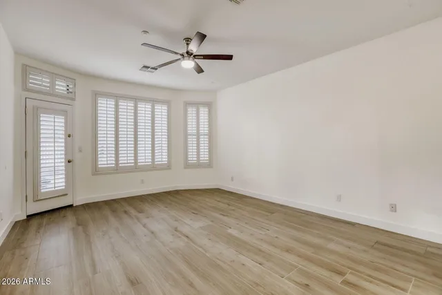 a view of empty room with wooden floor and fan