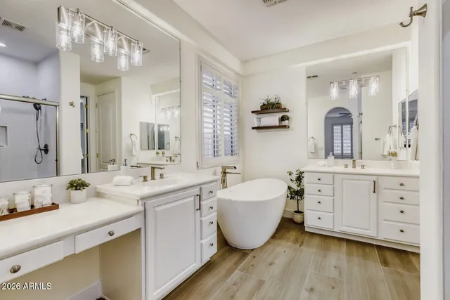 a spacious bathroom with double vanity sink a two mirror a window a bathtub and vanity