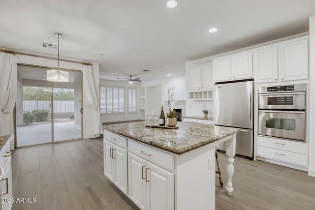 a kitchen with stainless steel appliances granite countertop a refrigerator a sink a stove and a refrigerator