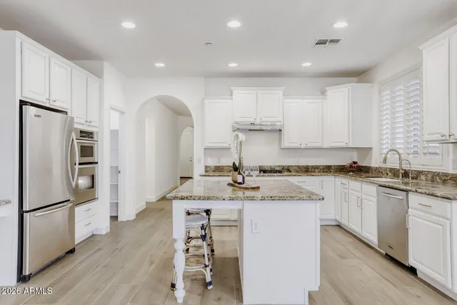 a kitchen with stainless steel appliances granite countertop a refrigerator sink and white cabinets