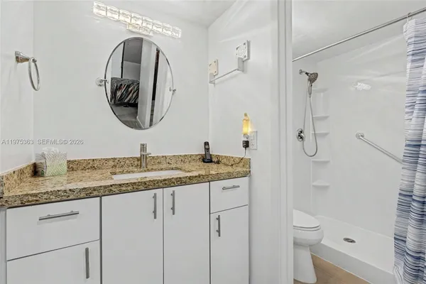 a bathroom with a granite countertop sink a toilet and a mirror