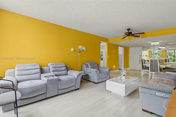 a living room with couches and kitchen view with wooden floor