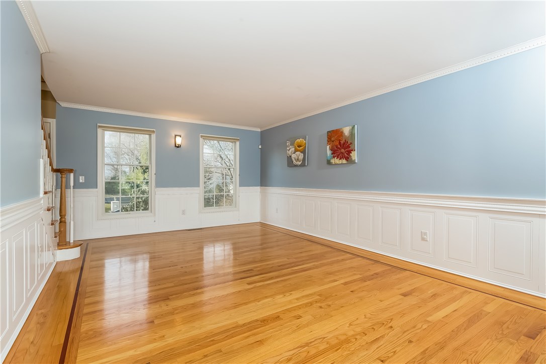 Large open Living Room/Dining Room space with gleaming hardwood flooring, Wainscoting and Crown molding