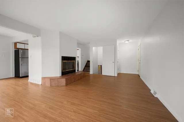a view of empty room with wooden floor and fireplace