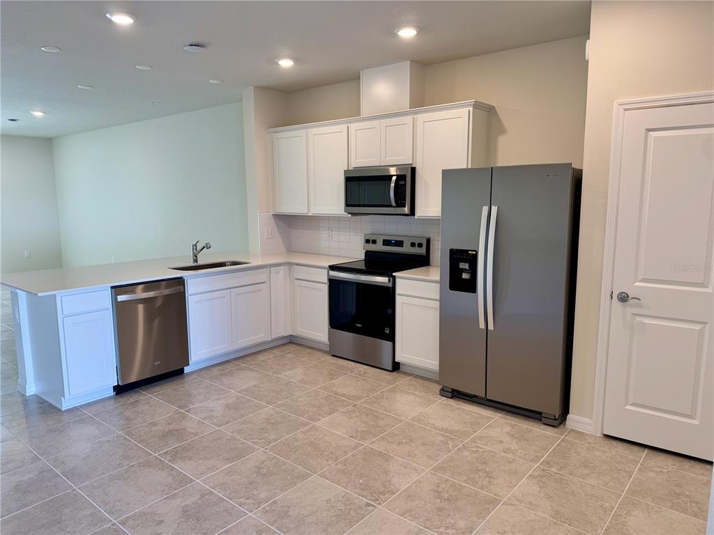 3059 Emerald Acrs Lane Sanford, FL 32771 - Photo 4 of 24 a kitchen with stainless steel appliances a refrigerator a sink a stove top oven and cabinets