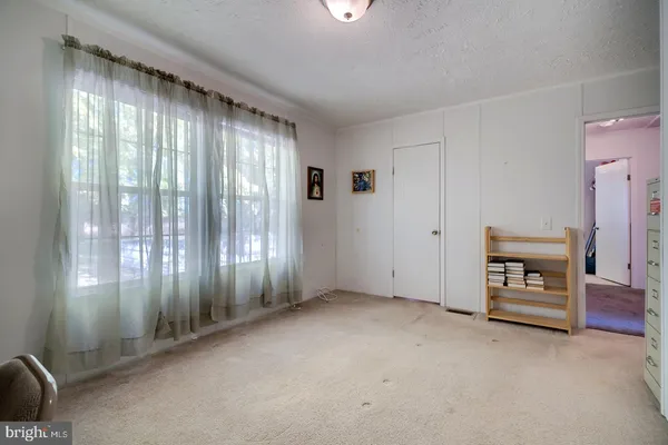 a bedroom with a bed table chair and a window