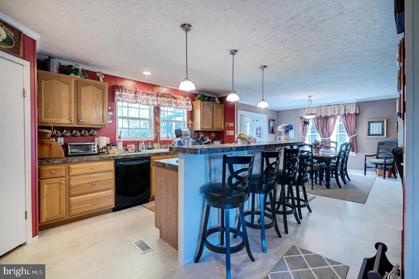 a kitchen with stainless steel appliances granite countertop a stove top oven a sink a dining table and chairs with wooden floor