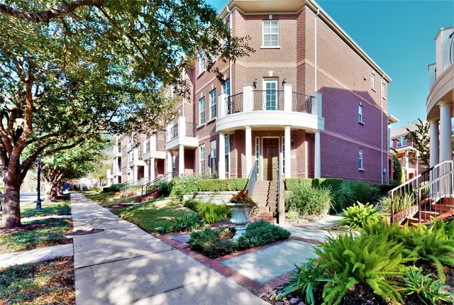 a front view of a multi story residential apartment building with yard and green space