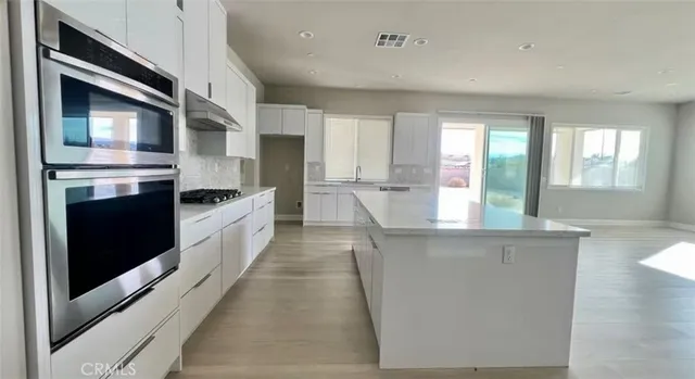 a large kitchen with stainless steel appliances wooden floor and a window