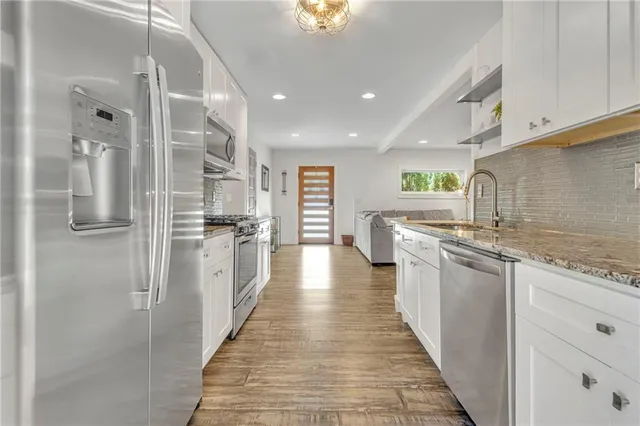 a kitchen with stainless steel appliances granite countertop a refrigerator and a sink