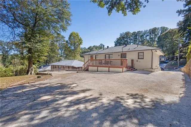a view of a white house with a yard and large trees