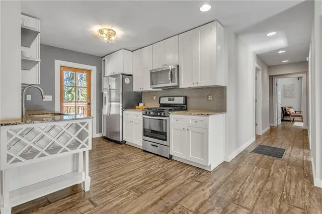a kitchen with stainless steel appliances wooden floors and white cabinets