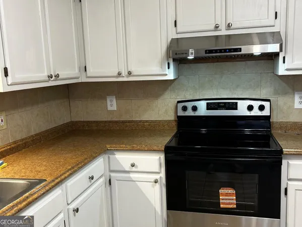 a kitchen with granite countertop white cabinets and black appliances