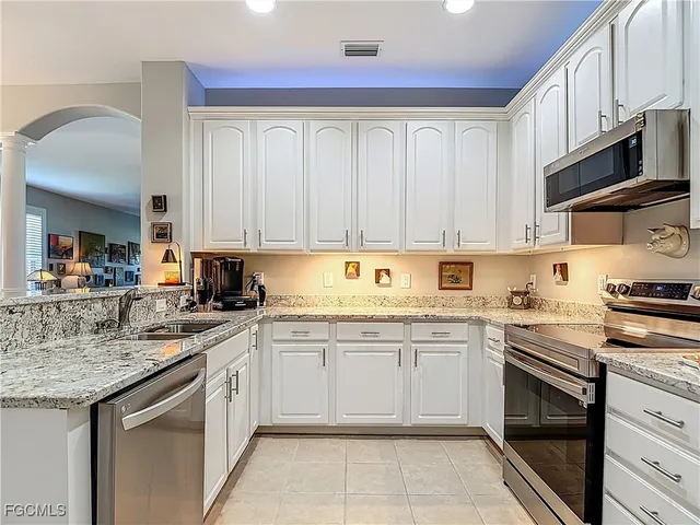 a kitchen with stainless steel appliances granite countertop a sink and dishwasher a stove top oven with white cabinets
