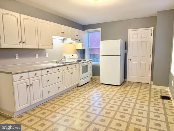 a kitchen with white cabinets and white appliances