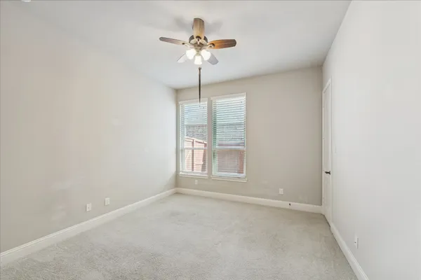 an empty room with a chandelier fan and windows