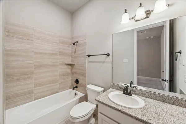 a bathroom with a granite countertop sink toilet mirror and bathtub