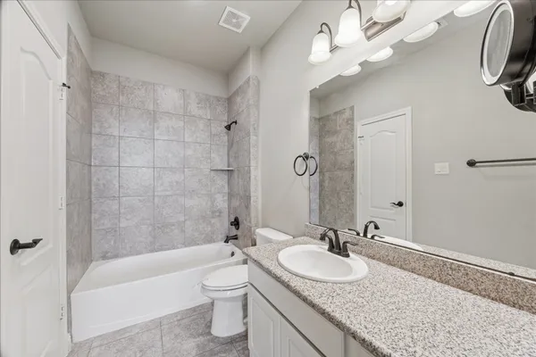 a bathroom with a granite countertop bathtub a sink a toilet a mirror and shower